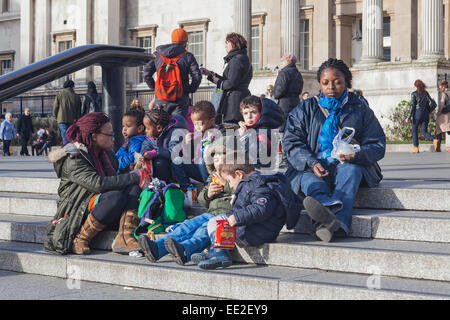 Trafalgar Square Londres, un groupe d'enfants de l'école primaire de détente avec leurs enseignants Banque D'Images