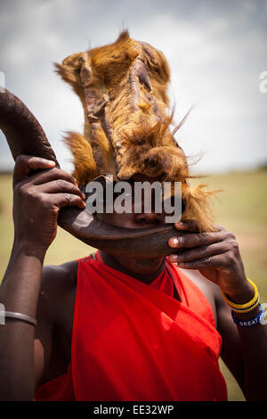 Guerrier Masai portant chapeau fait de peau de lion dans le Masai Mara, Kenya Banque D'Images