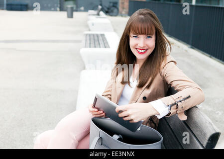 Jeune femme assise sur un banc à l'extérieur, Munich, Bavière, Allemagne Banque D'Images