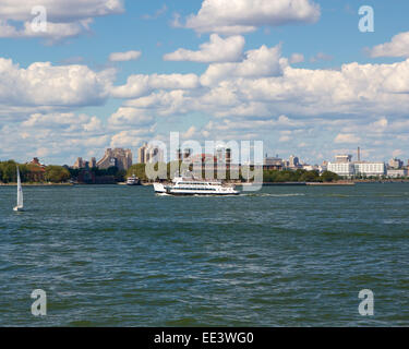 NYC Statue bateau de croisière passe par Ellis Island à New York, NY, USA d'une belle journée d'automne en 2012. Banque D'Images