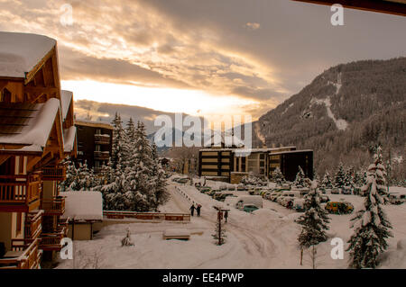 Les rues couvertes de neige et de chalets dans une station de ski française après le coucher du soleil. Banque D'Images