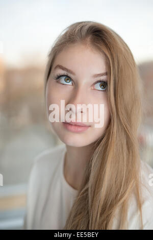 Portrait d'une jolie fille de l'adolescence. Elle est levant les yeux vers le haut et à la recherche. Banque D'Images