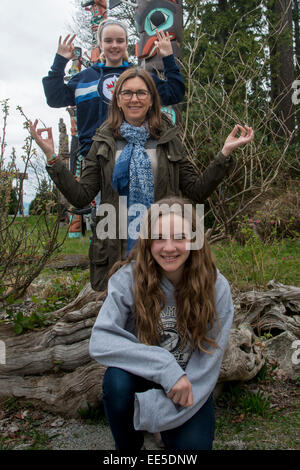 Femme avec ses filles posant devant de totems au parc Stanley, Vancouver, British Columbia, Canada Banque D'Images