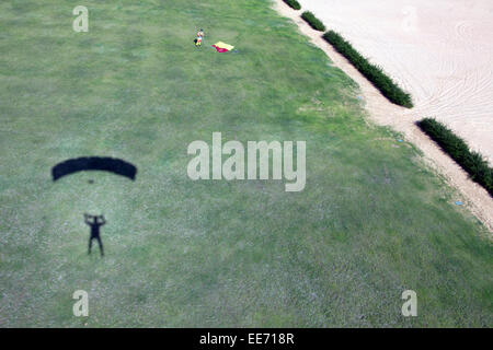 Parachutiste sous voile s'approche de la zone d'atterrissage. Ce qui est son ombre montrant la façon de voler pour une sauvegarde d'atterrissage. Banque D'Images