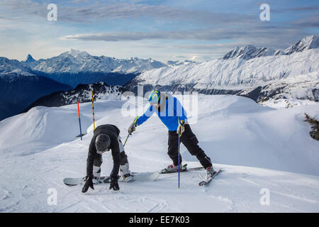 Aider skieur snowboarder maladroit avec casque de ski pour rester droit sur la pente de ski de sports d'hiver dans les Alpes Banque D'Images