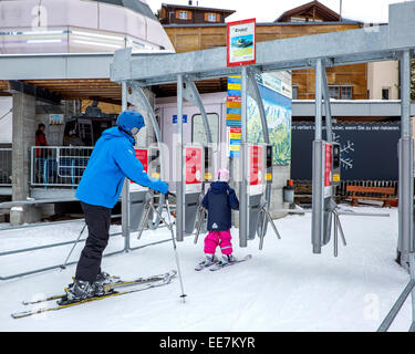 Ski père et fils avec les casques de ski, la station de télécabine entrée station de sports d'hiver à Riederalp, Valais / Valais, Suisse Banque D'Images