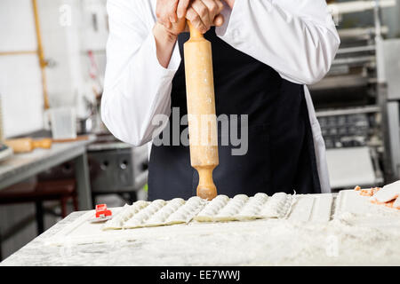 Chef holding Rolling pin en position debout au comptoir dans la cuisine Banque D'Images