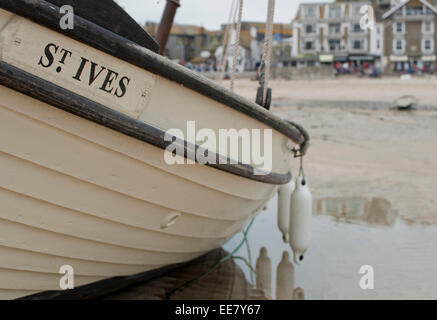 Un bateau enregistré pour le port de St Ives, Cornwall est vu à marée basse.La ville de St Ives, Cornouailles est vu dans l'arrière-plan. Banque D'Images