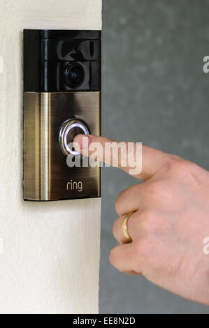 Un homme appuie sur le bouton d'un 'Ring' porte vidéo internet-bell, de ring.com. Banque D'Images