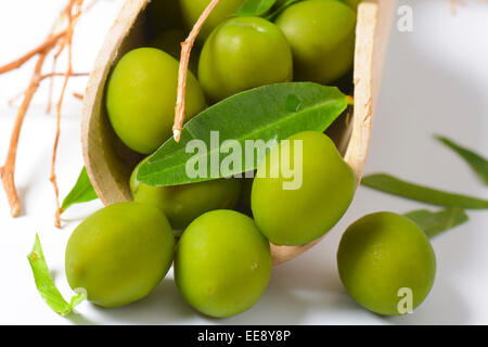 Olives vertes brutes sur cuillère en bois Banque D'Images