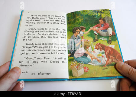 Personne tenant un livre de lecture pour enfants de Ladybird, apprenant à lire Banque D'Images