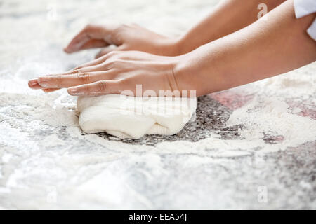 Femme chef's hands kneading dough at counter Banque D'Images