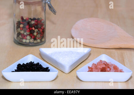 Trois types de sel et de poivre de couleur avec une cuillère de cuisine Banque D'Images