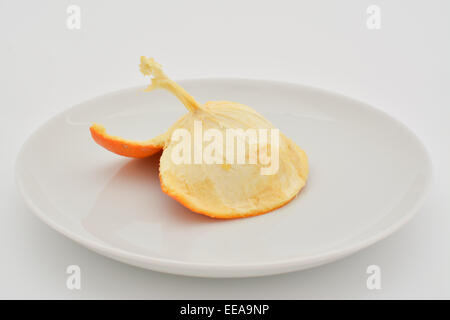 L'intérieur de la peau d'une orange mangée sur une plaque blanche Banque D'Images