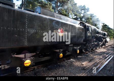 Le conducteur de 9F 2-10-0 numéro de la Locomotive à vapeur 92203 'Black Prince' vérifie la route en avant car il va autour de son train à la gare de Holt sur le North Norfolk de fer entre Holt et Sheringham, près de Norwich, Norfolk. Le célèbre chemin de fer et des animaux Artiste David Shepherd restauré cette machine à vapeur en état de fonctionnement. Banque D'Images