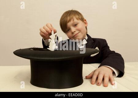 Jeune garçon habillé en magicien tirant un lapin de son chapeau haut de forme Banque D'Images