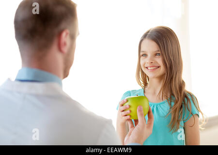 Médecin homme donnant une pomme pour smiling little girl Banque D'Images