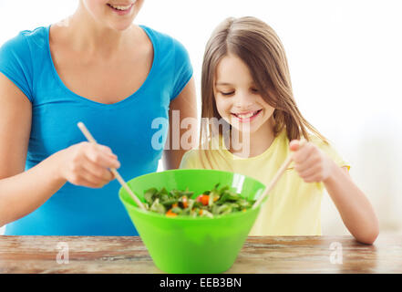 Petite fille avec la mère dans la cuisine salade mélange Banque D'Images