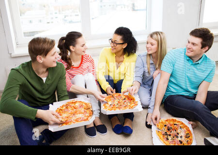 Cinq adolescents souriants de manger une pizza à la maison Banque D'Images