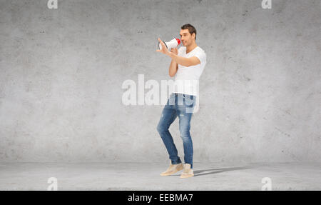 Handsome man with megaphone sur mur de béton Banque D'Images