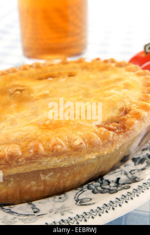 Une tarte de viande salés d'or sur une plaque d'antiques et verre de bière Banque D'Images