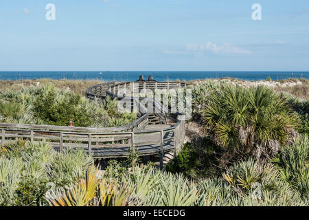 Promenade en serpentin en bois traversant l'habitat côtier des dunes de sable, on a vu des palmettos et de l'avoine de mer avec l'océan en arrière-plan, Daytona Beach. Banque D'Images