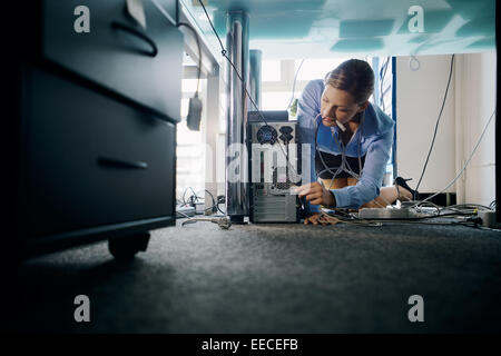 Assistante working in office, brancher des câbles d'équipements informatiques et électroniques, de déconner avec les fils. Copy space Banque D'Images