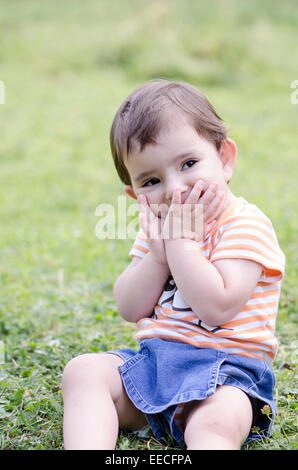 Little girl sitting on grass and smiling Banque D'Images