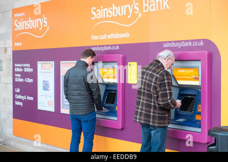 Sainsbury's distributeur automatique de billets dans leur magasin à Matlock, Derbyshire, Angleterre, avec deux hommes utilisant les distributeurs automatiques Banque D'Images