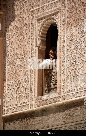 Le bras de l'homme et chemise blanche incliné vers l'extérieur d'une fenêtre voûtée de style arabe à Marrakech avec les fils de l'Architecture Islamique. Banque D'Images