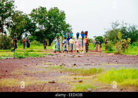 Groupe de femmes et d'enfants du village de retour après le lavage des vêtements dans la rivière, au Mali. Banque D'Images