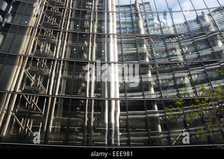 Le bâtiment de la Lloyds reflétée dans l'architecture moderne d'un édifice de verre en face de la ville de Londres, Royaume-Uni. Cette petite région est bien connue pour son design architectural novateur. Banque D'Images