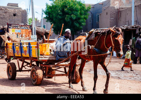Homme voyageant sur un chariot à cheval dans les rues de Djenné, au Mali. Banque D'Images