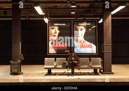 Homme assis sur un banc dans une station de métro de Paris, France Banque D'Images