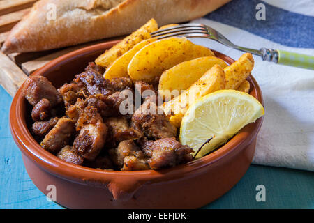 La viande de porc frit avec des frites et citron servi en pot en argile Banque D'Images