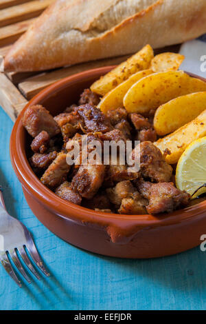 La viande de porc frit avec des frites et citron servi en pot en argile Banque D'Images