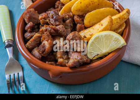 La viande de porc frit avec des frites et citron servi en pot en argile Banque D'Images