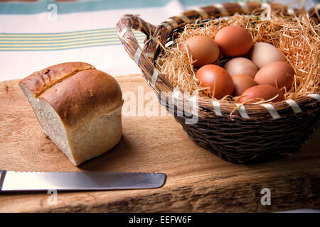 Miche de pain et panier d'oeufs de poulet fraîchement posées Banque D'Images