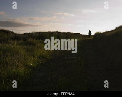 Femme entre dans le coucher du soleil sur la lande. Banque D'Images