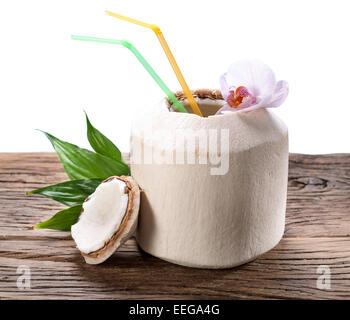 L'eau de noix de coco dans la noix sur une vieille table en bois. Fichier contient des chemins de détourage. Banque D'Images