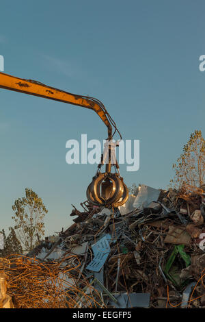 Crane holding ferraille sur haut de pile de junk Banque D'Images