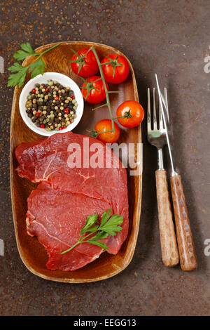 La viande de boeuf cru frais avec du poivre et des herbes sur plaque de bois Banque D'Images