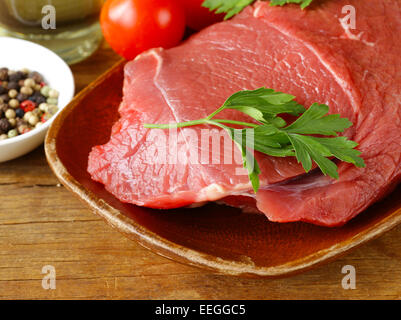 La viande de boeuf cru frais avec du poivre et des herbes sur plaque de bois Banque D'Images