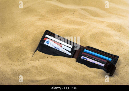 Wallet abandonné et à moitié enfoui sur une plage de sable. Banque D'Images