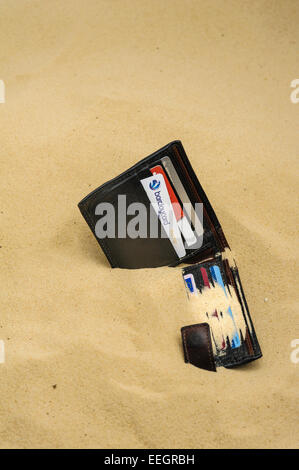 Wallet abandonné et à moitié enfoui sur une plage de sable. Banque D'Images