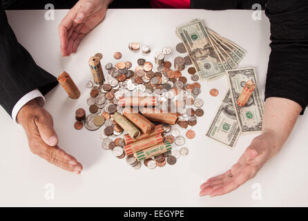 US Coins. Les projets de loi, et Coin Rolls avec mains et bras regroupant l'argent Banque D'Images