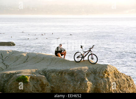 Cycliste solitaire donnant sur surfers sur California coast Banque D'Images