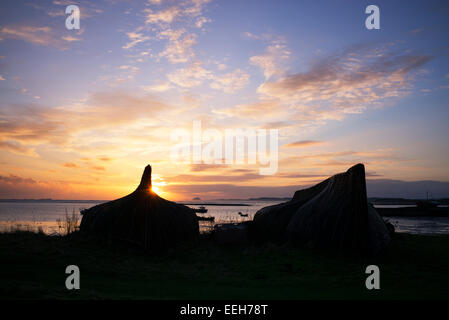 Bateau de hareng cabanes dans le port au lever du soleil sur l'Île Sainte, Lindisfarne, Northumberland, Angleterre. Silhouette Banque D'Images