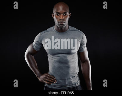 Portrait of muscular young man in sportswear looking at camera sur fond noir. Les pays africains qui pose l'athlète confiant Banque D'Images