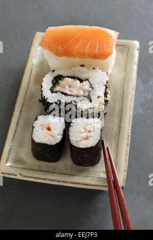 Maki, nigiri Uramaki & sushi au saumon et gambas sur un plat de céramique japonais laqué avec baguettes, ardoise naturelle backg Banque D'Images